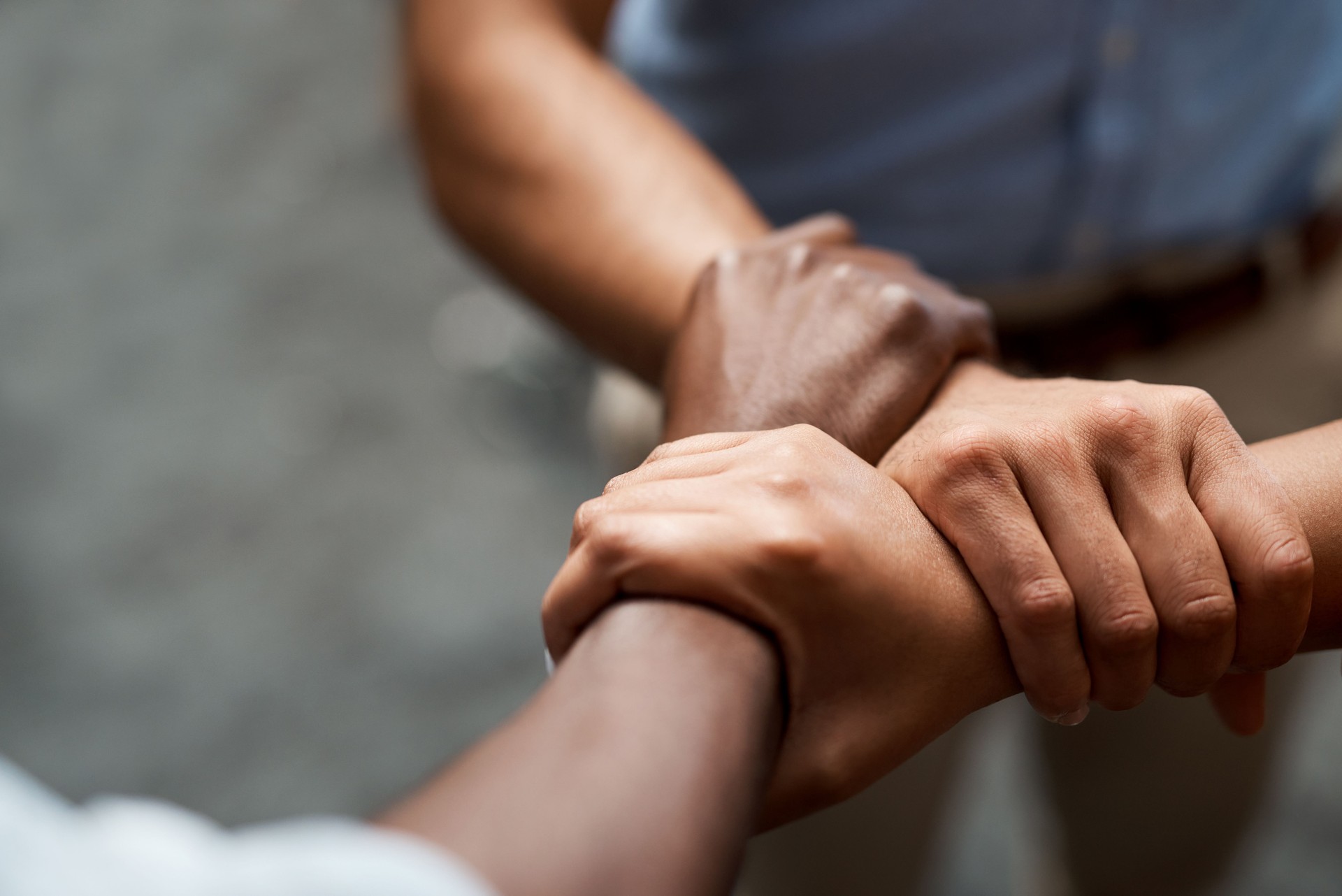 Shot of a group of businesspeople linking arms in solidarity in a modern office